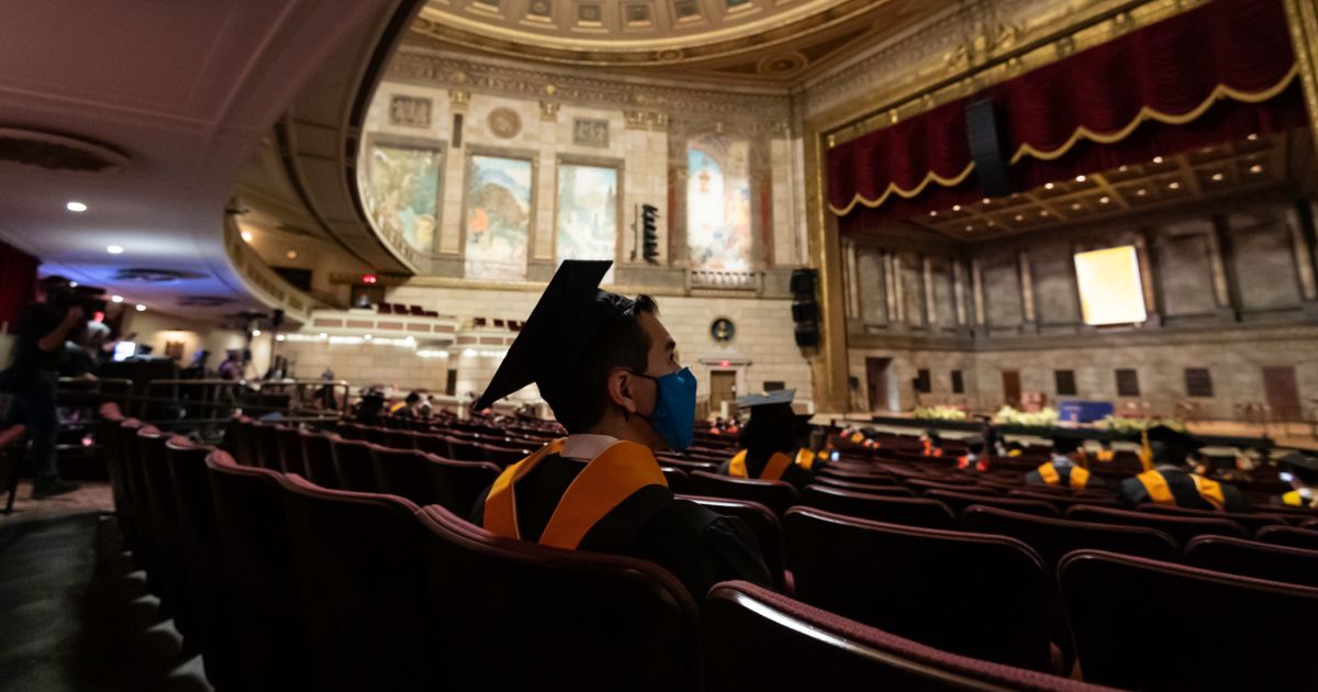 student sitting at masters commencement